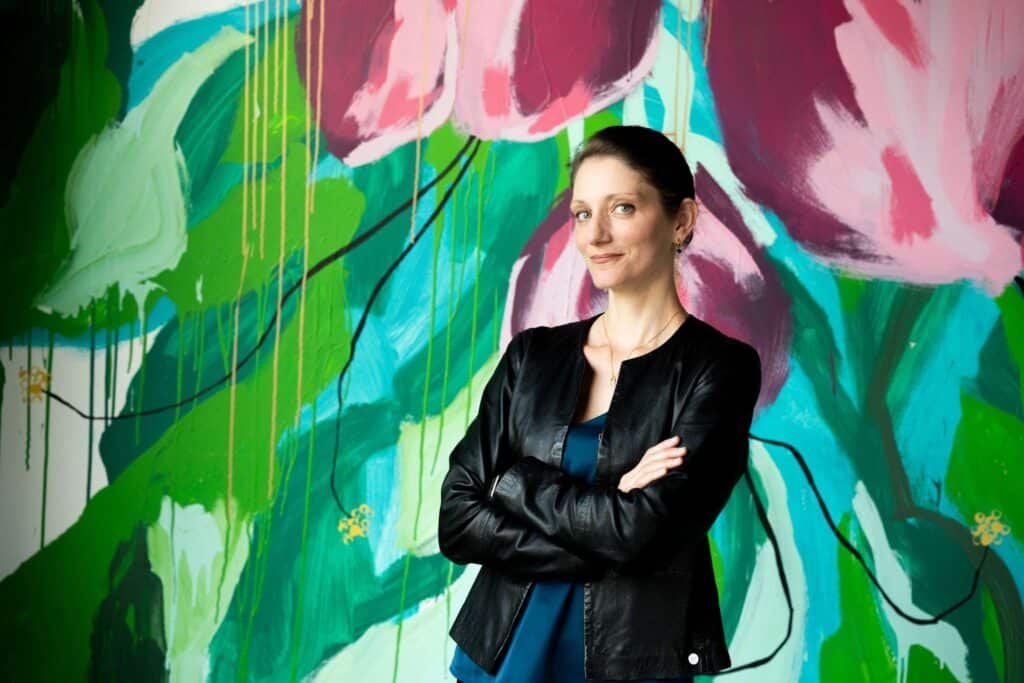 Vanessa Rose standing in front of a colorful mural, newly appointed President and CEO of New Music USA