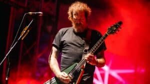 Brent Hinds of Mastodon performing live on stage with guitar under red lights