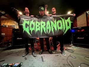 Cobranoid Denver metal band holding banner on stage with Marshall amps in the background