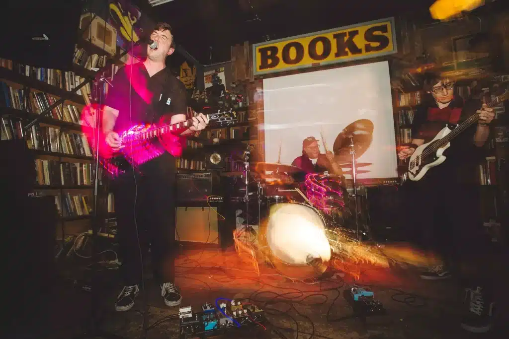 Replica City Denver band performing live at Mutiny Information Cafe, featuring Corey Fruin on guitar and vocals, Matt Dunne on bass, and Nathan Rodriguez on drums