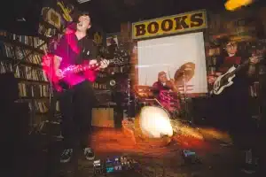 Replica City Denver band performing live at Mutiny Information Cafe, featuring Corey Fruin on guitar and vocals, Matt Dunne on bass, and Nathan Rodriguez on drums