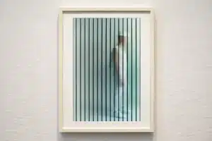 Framed conceptual artwork featuring a side profile of the Neon the Bishop character in a white outfit seen through vertical optical illusion lines