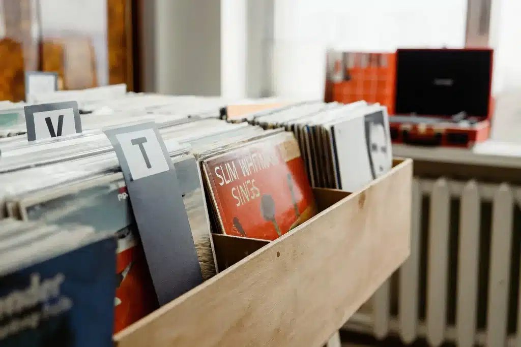 Wooden crate used to store vinyl records with dividers and a portable player in the background.