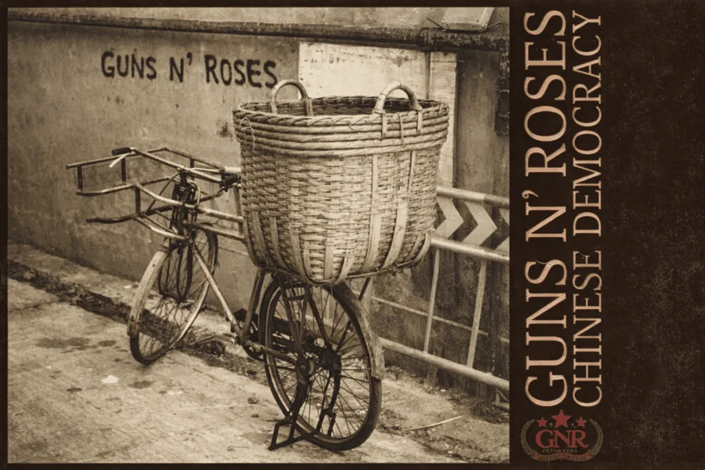 Album cover art for Guns N' Roses Chinese Democracy featuring a sepia-toned bicycle with a wicker basket against a graffiti wall